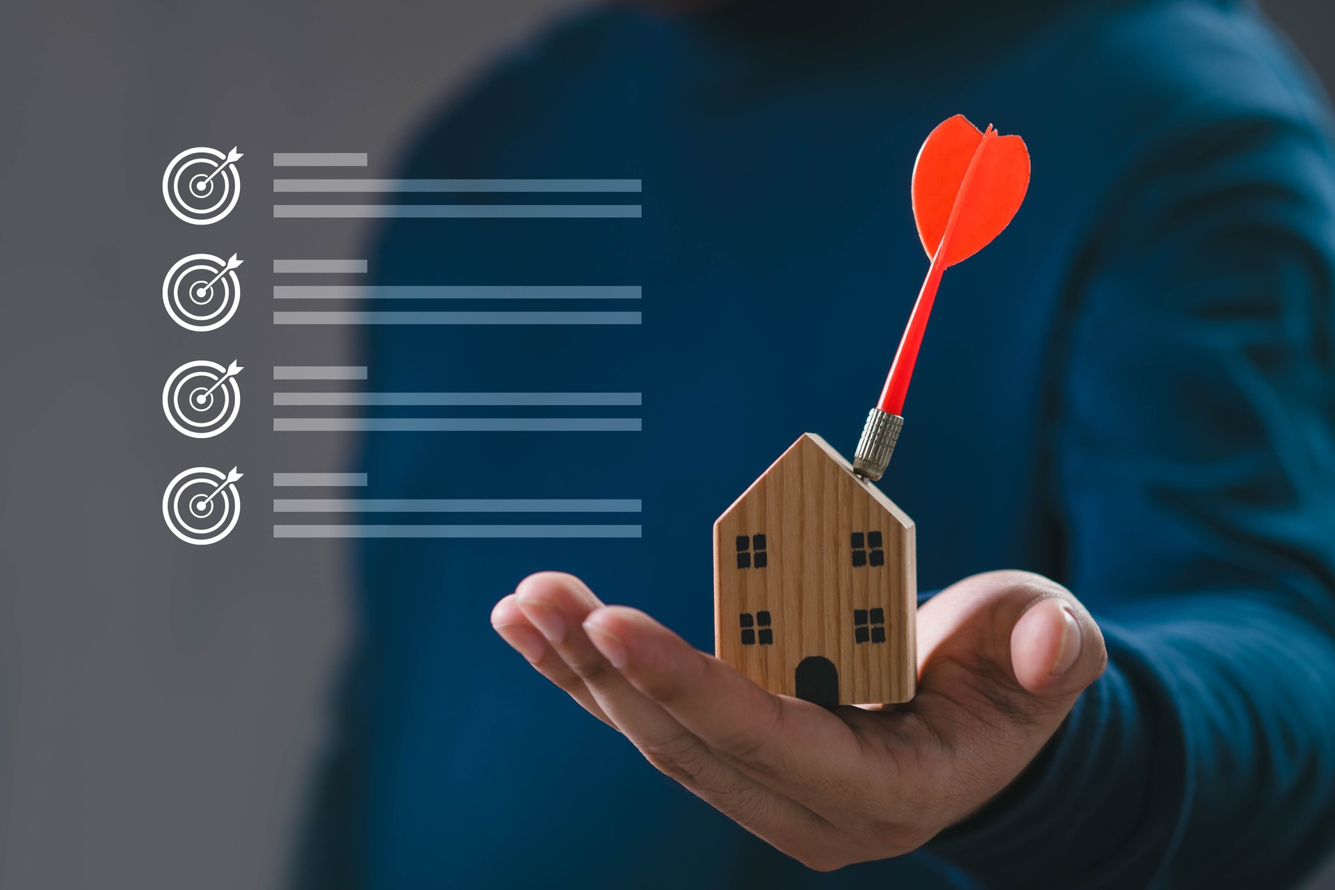 Mano che tiene un modello di casa in legno con una freccia rossa, che simboleggia il marketing immobiliare, l'obiettivo di investimento immobiliare, la strategia aziendale, l'obiettivo abitativo e il concetto di proprietà della casa di successo.